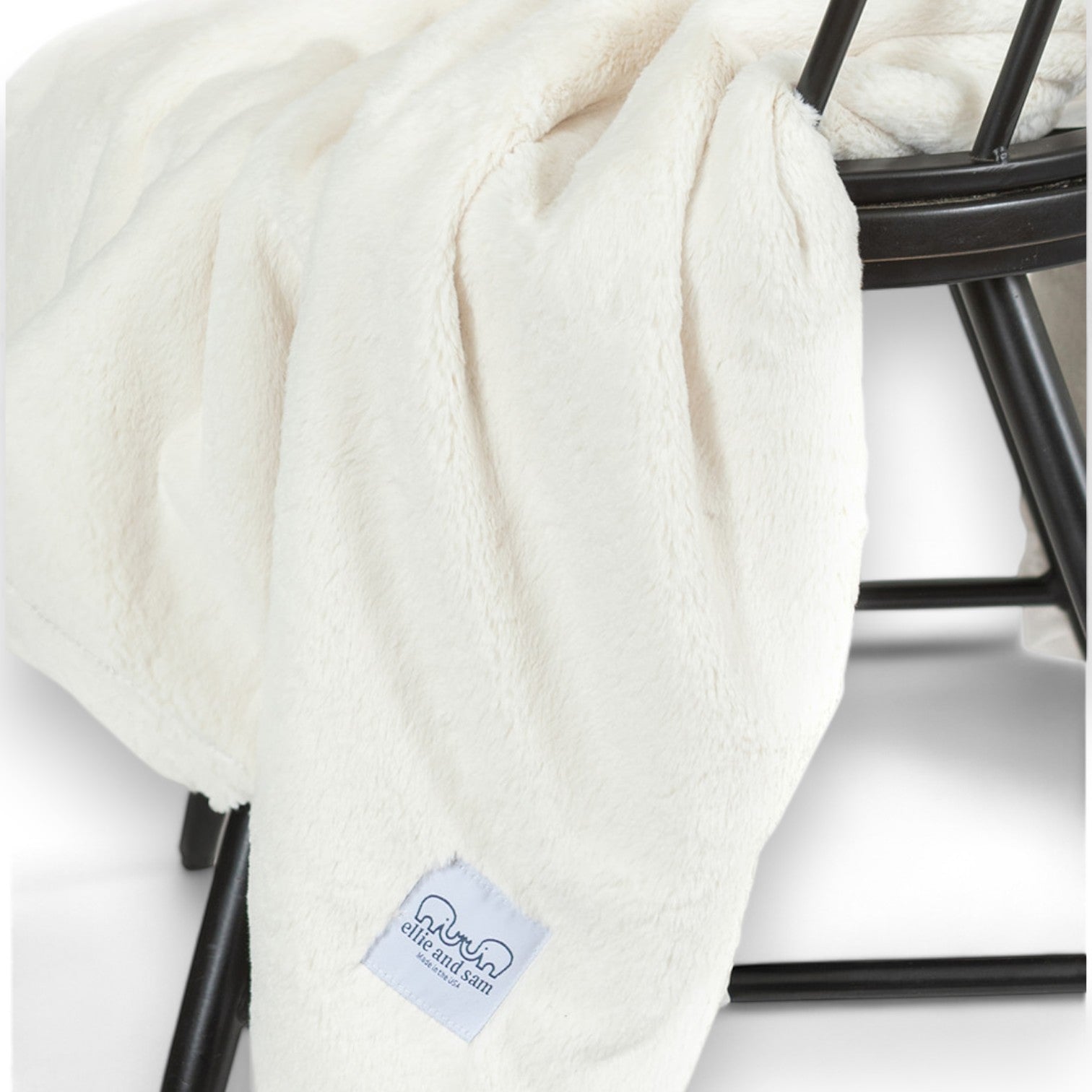 Luxury Borderless Throw Blanket in Ivory draped over a black chair, showcasing its soft texture and elegant design.